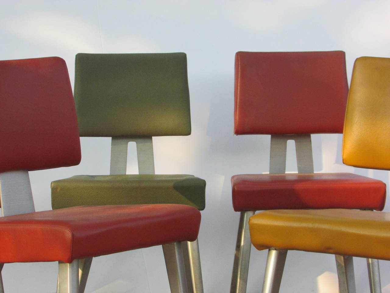 A very colorful grouping of six all original General Fireproofing / Goodform task chairs with period vinyl green / yellow gold and coral red upholstered seats and backs. Four of the chairs with cut out design aluminum back rails / two with aluminum