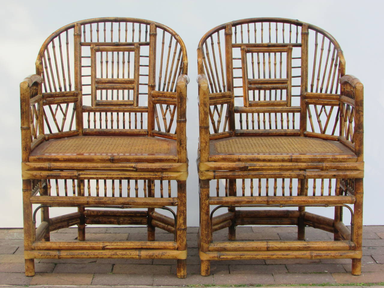 A pair of Brighton Pavillion Chinese Chippendale style burnt bamboo rattan armchairs with wood and pressed cane seats. Both chairs in beautifully aged all over original glowing tortoise shell like color.