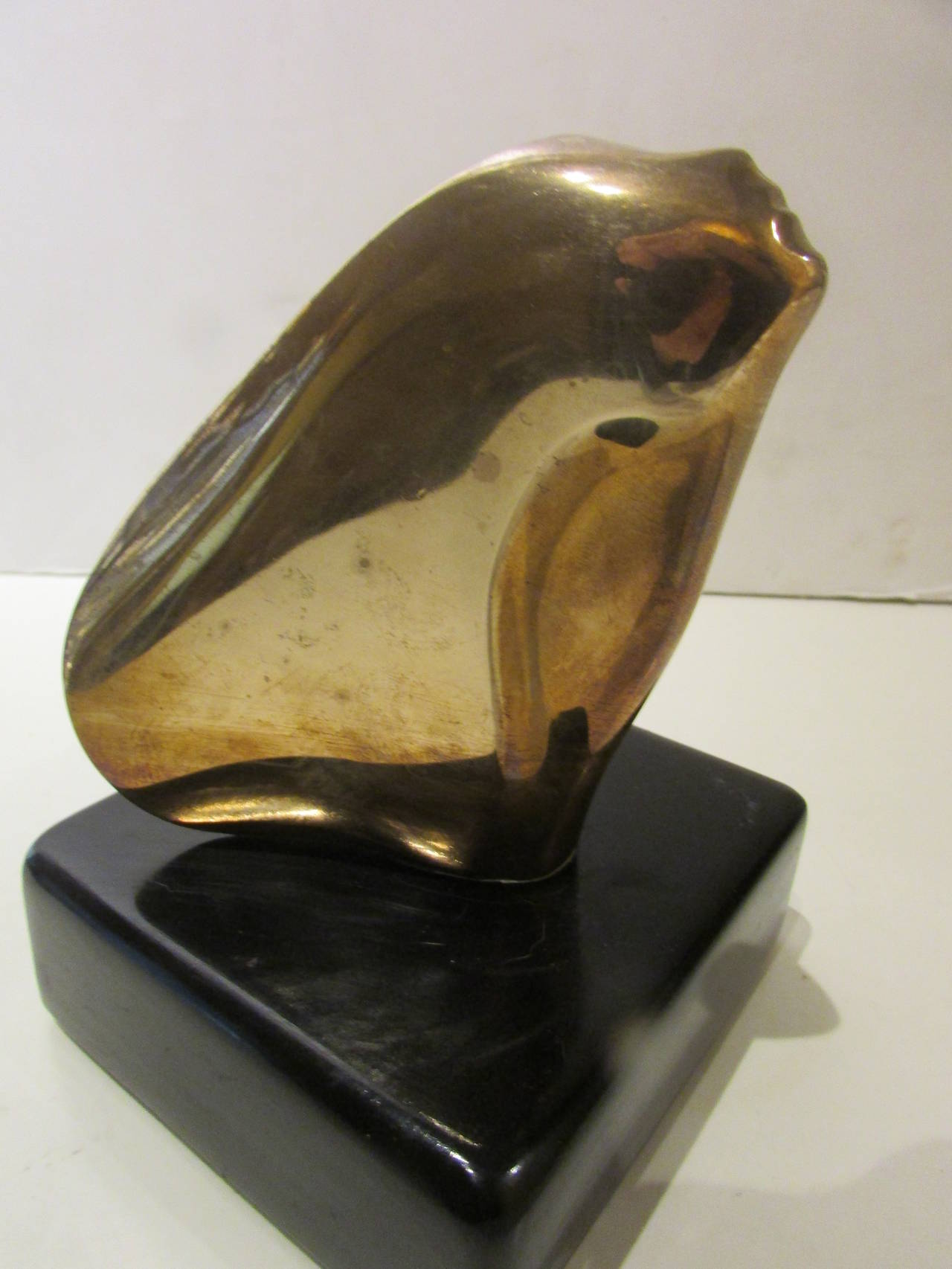 A mid-20th century modernist French bronze sculpture of a sleek flowing woman's face ( titled - The Kiss ) mounted on the original black lacquered wood base - signed on lower back of bronze - G. Charpentier 7/8 with monogram - underside with signed