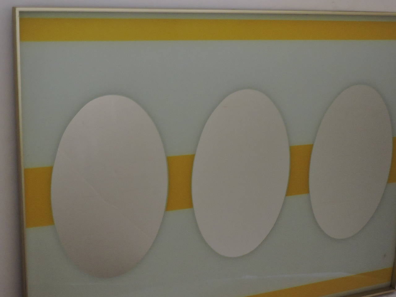 A great looking high quality large op art mirror with three central oval mirrors set within a striped yellow and white reverse painted glass field housed in a thick brass frame work. American, circa 1960 - 1970. Look at all pictures and read