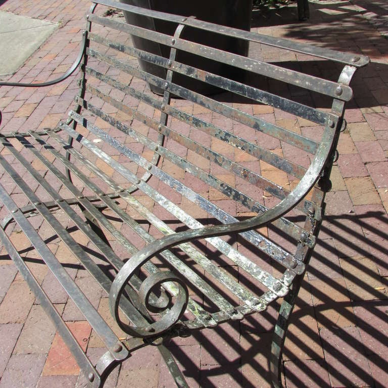 Antique classical form hand wrought strap iron curved arm garden bench - riveted construction with beautifully aged surface showing areas of worn paint & raw iron from many years of outdoor use. Structurally perfect. Dates from the late 19th century