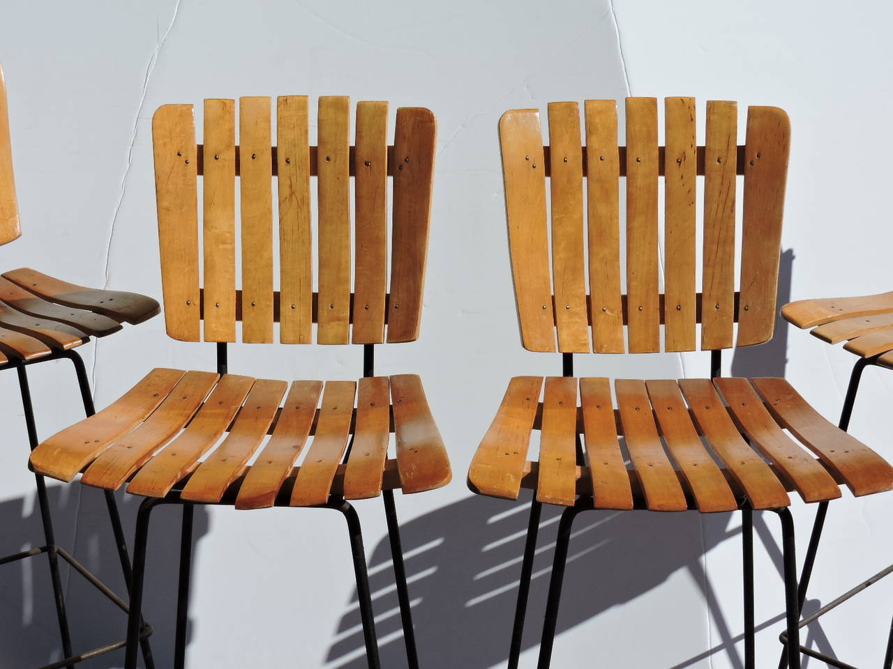 A matched set of four 1960's wood slat and black iron bar stools by Arthur Umanoff.