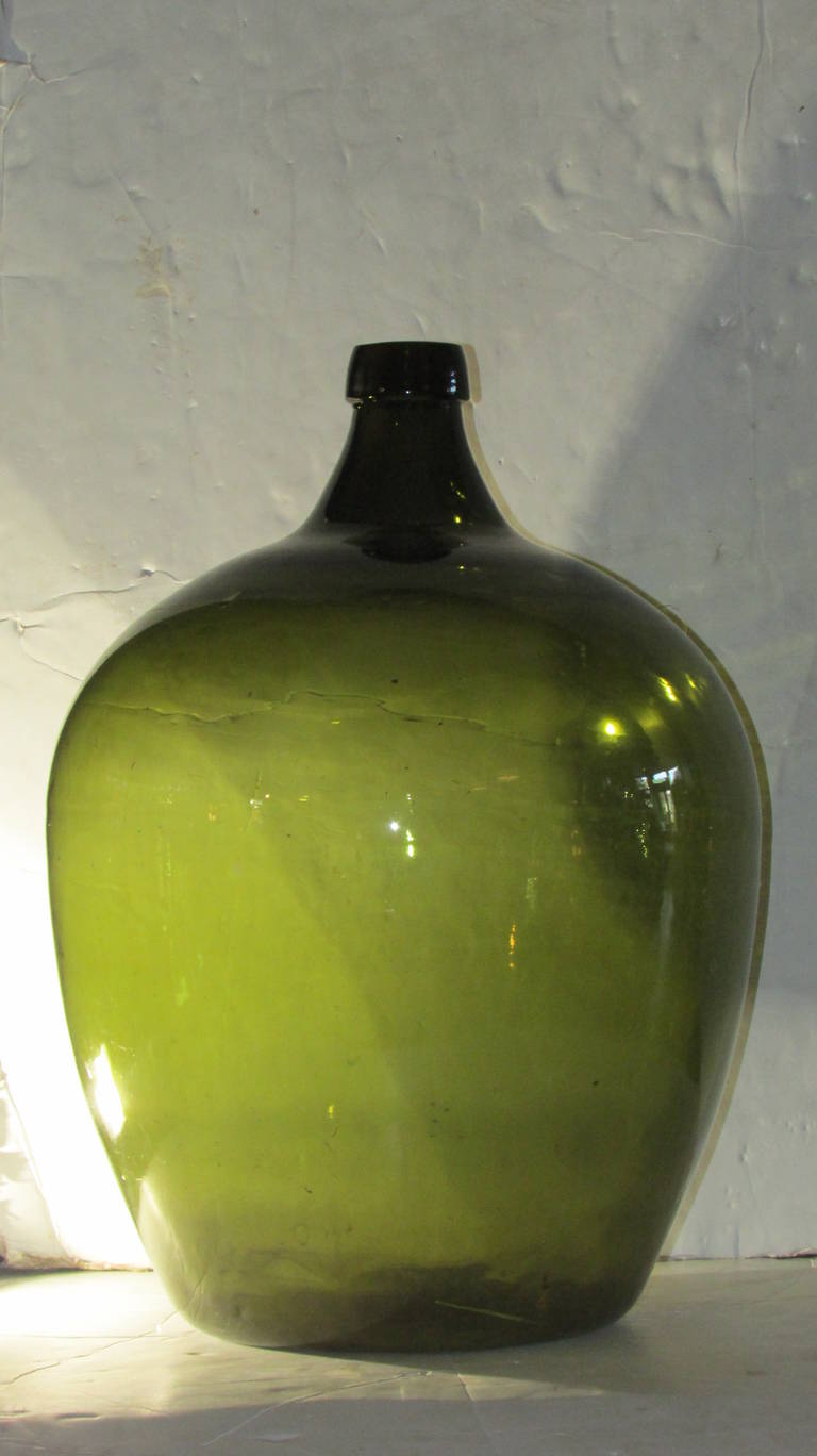 An emerald green blown glass demijohn for wine - measuring 24 inches high by 16 inches at widest point.- dates from the 19th century and most likely French in origin.