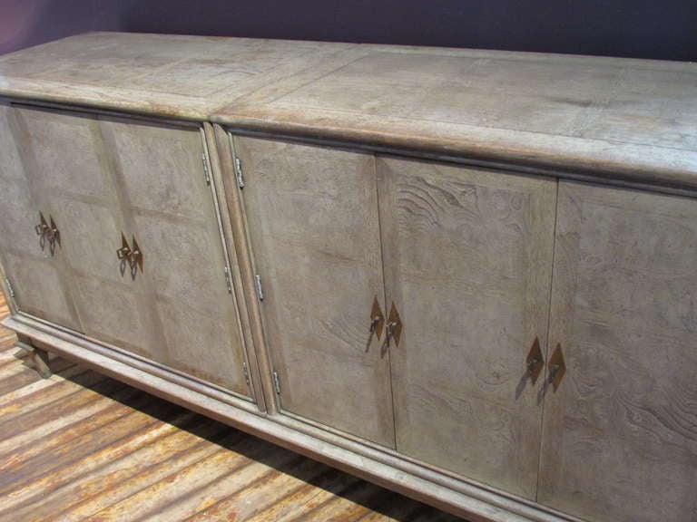 A Mastercraft credenza with a beautifully aged cerused parchment vellum colored factory finish to amboyna burl wood front, grained wood top & sides. Copper metal mounts at the top of the four pyramidal tapered legs, copper caps at bottom of the four