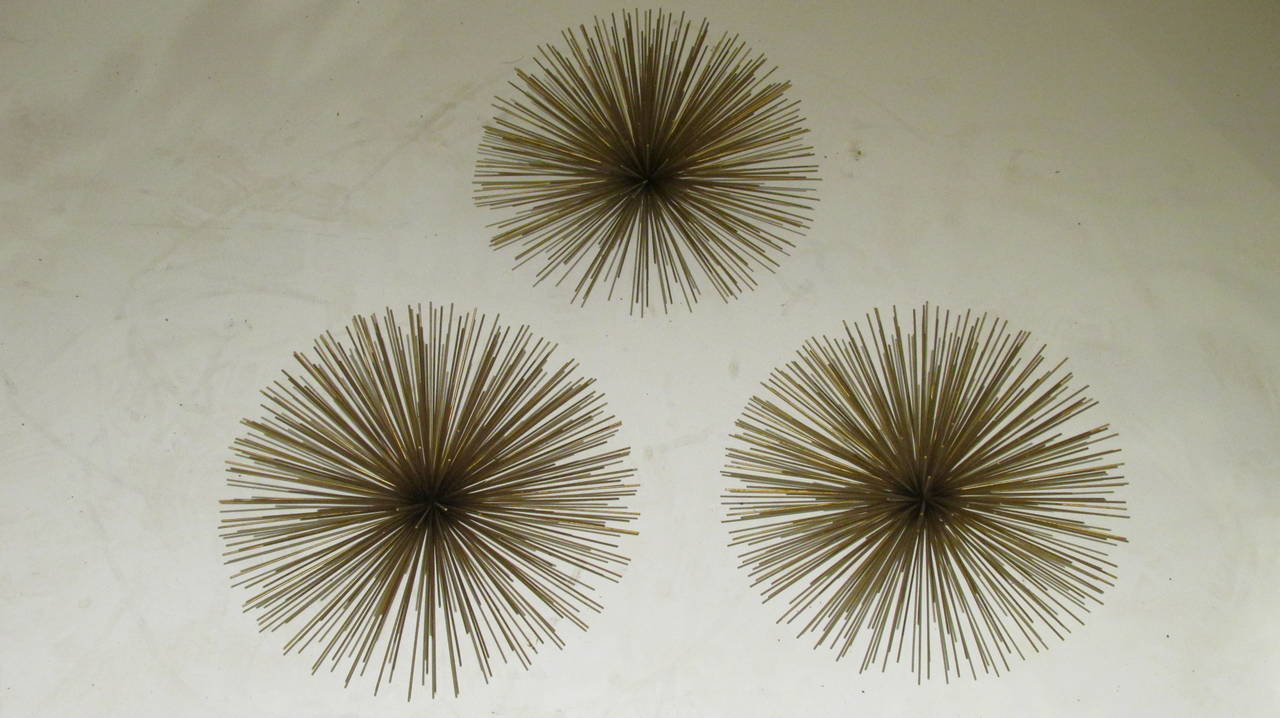 Three gilt metal sea urchin form / pom pom sculptures by Curtis Jere. They are in excellent clean bright condition and have the original hooks on the back for wall hanging
