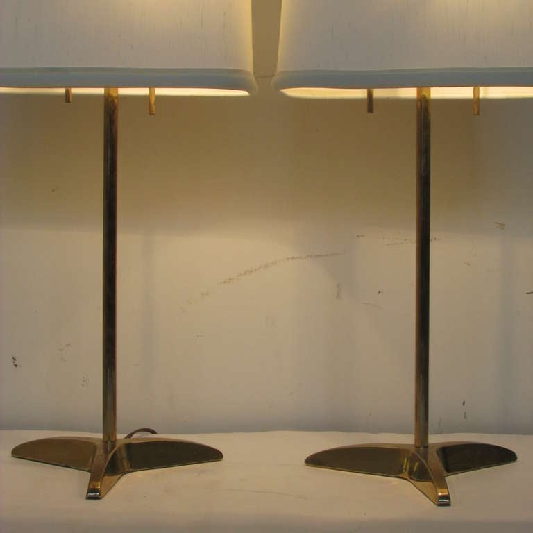 A pair of minimal modernist brass tripod base table lamps by Gerald Thurston for Stiffel. Circa 1960. Very good original condition..The Stiffel silver foil labels present. Shades for display only.