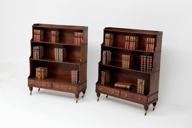 A pair of mahogany graduating bookshelves with galleried tops and grooved rims. Each base fitted with a pair of short drawers which are cedarwood lined. Brass knob handles are later.
Raised on small turned legs with brass castors. 