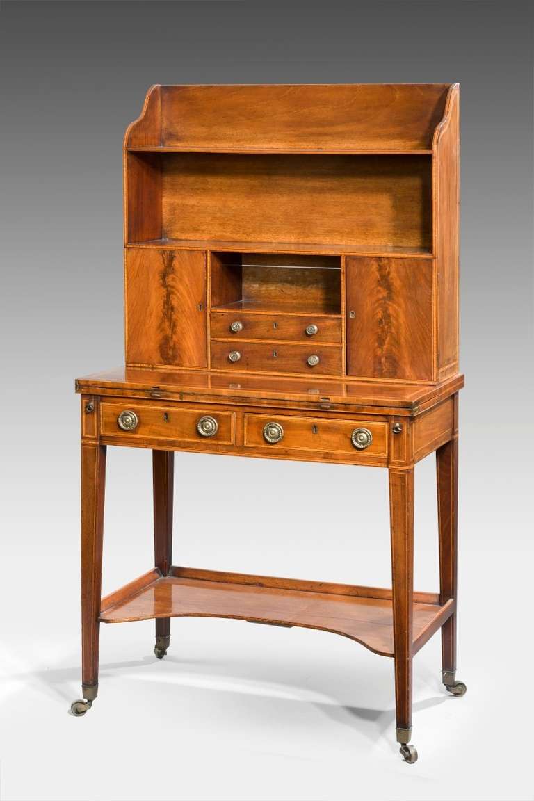 A fine quality Georgian 18th century Bonheur-du jour; In design by Thomas Sheraton. Veneered in mahogany and edged throughout in satinwood, box-wood and ebony. The leather lined writing flap folded over, two small drawers which are supported by