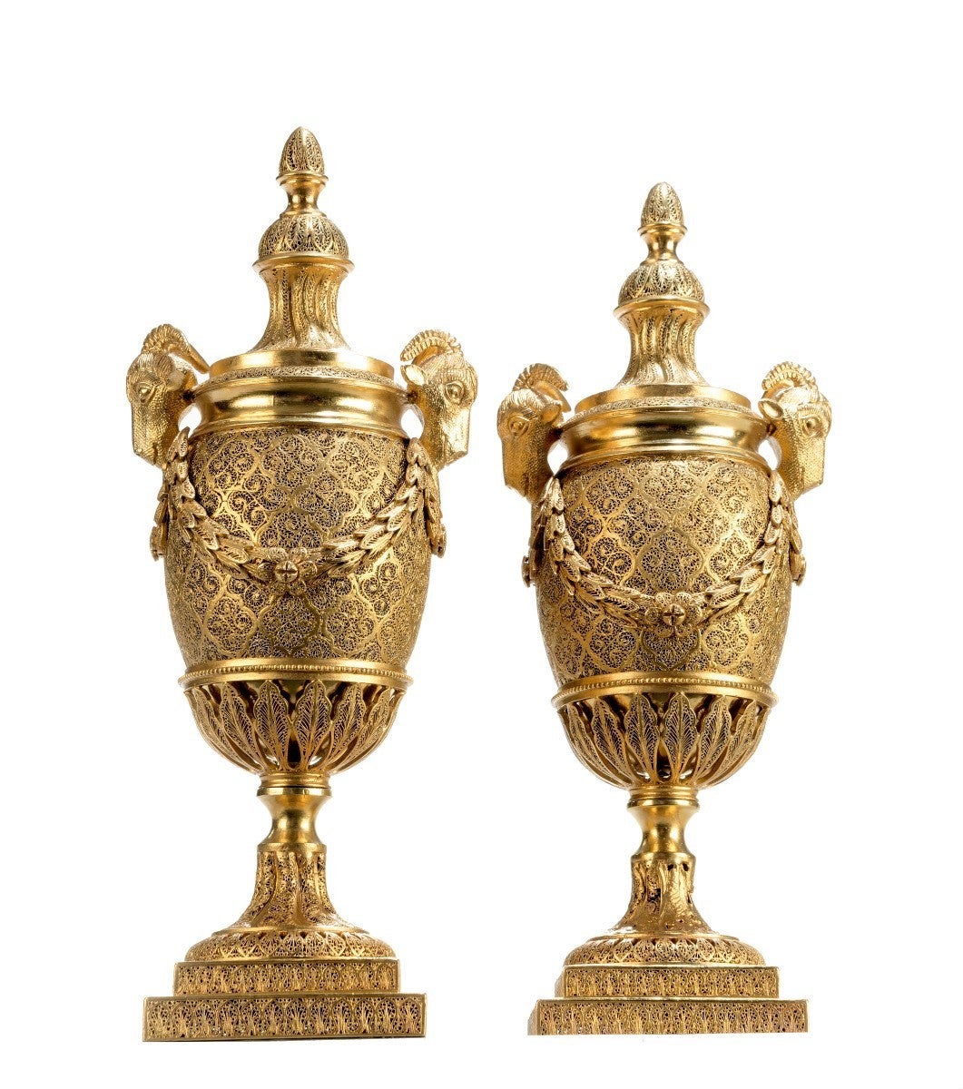 Pair of silver gilt filigree Goat's-Head candle vases after a design by Matthew Boulton; the tops are reversible to become candle-holders above an amphora-shaped body with swags flanking on either side from a pair of rams head masks on a short socle