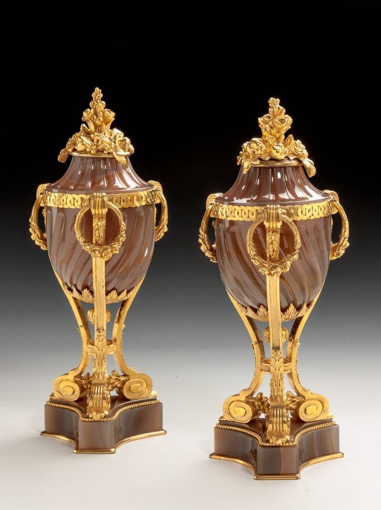 Ormolu mounted agate urns each with an incised carved body and covers. The casting and gilding is of the finest quality. Each is signed on the underside of the cover BV.