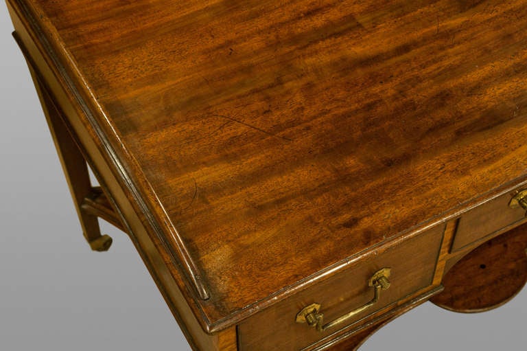 A fine George III mahogany and satinwood cross banded kneehole dressing table on taper legs to original castors with shaped under tier, the drawers with ebonised cockbeading and original gilt brasses.
