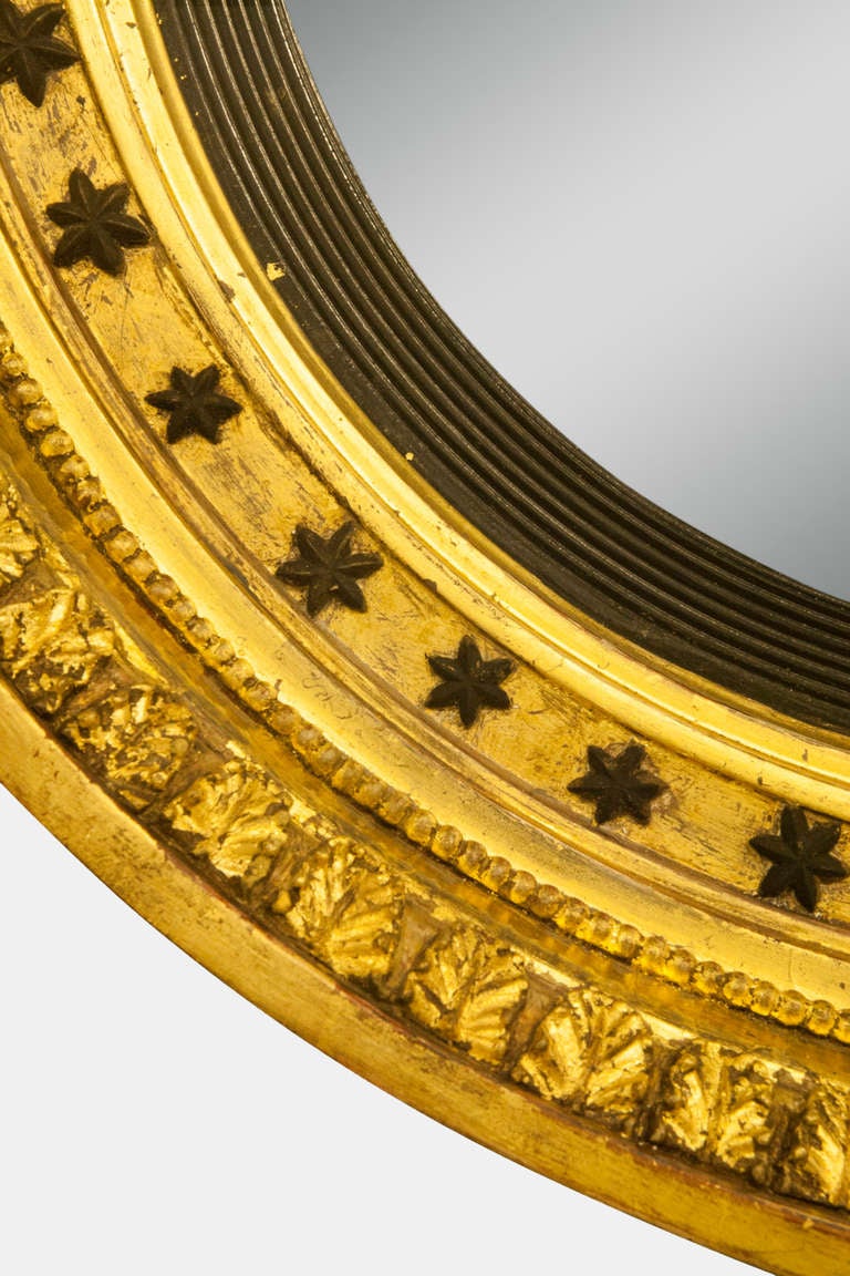 A regency convex mirror with star decoration and surmounted with an eagle