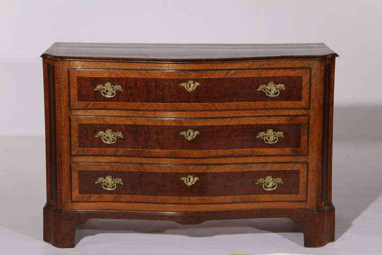 An 18th century Italian serpentine fronted commode in plum pudding mahogany with walnut crossbanding.