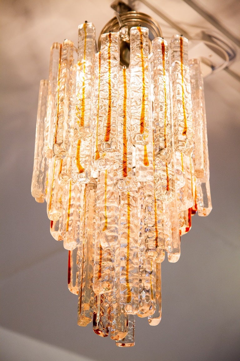 A stunning vintage Murano glass chandelier dating from the 1970's.
Textured glass bars Infused with amber. Textured on one side and smooth on the reverse, allowing them to be hung either way. In the photos the bars have the polished side facing