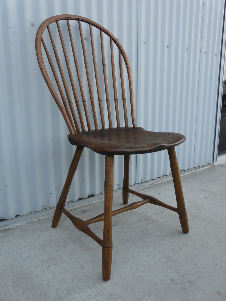 Very old windsor hoop back chair, hand hewn, having peg joints, steam moulded frame, the tapering bow having nine faux bamboo turned spindles piercing a thick plank saddle seat crisply undercut, raised on faux bamboo turned, splayed legs. Lovely