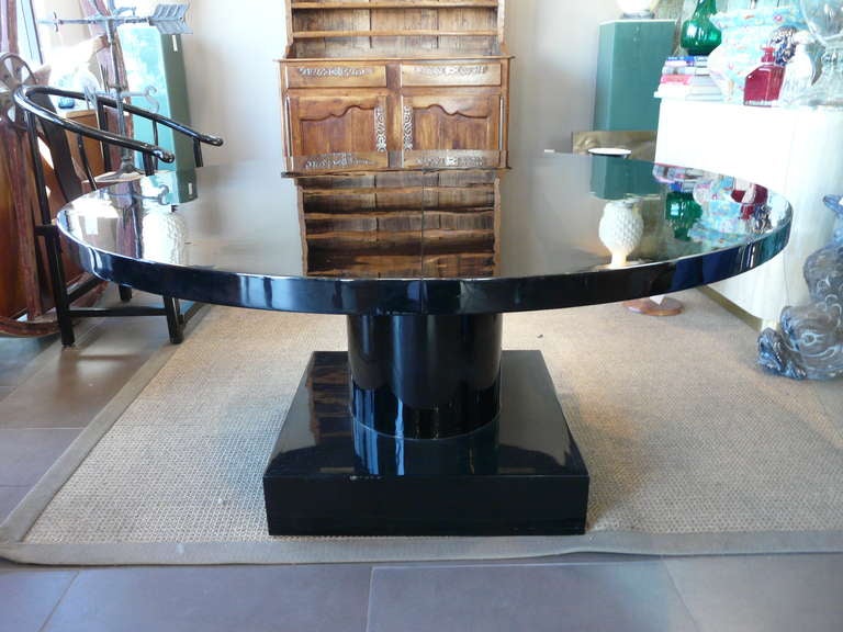 Fabulous foyer or dining table in black piano lacquer having center column rising from block plinth base, and glass top to protect surface.