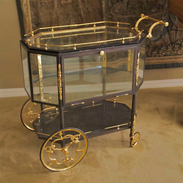 This is an exquisite Italian bar cart with a two tone finish of dore 
and patinated bronze. This item is in excellent condition complete with original glass and functional, maneuverable rubber tires. There is a large storage compartment with a