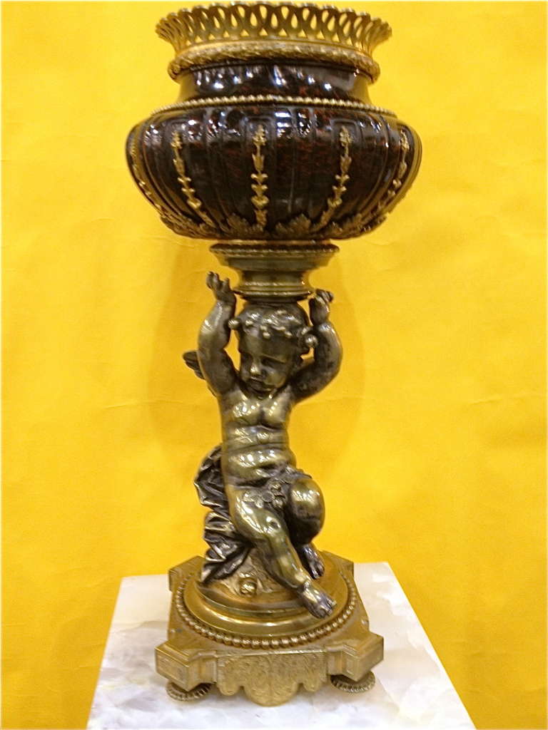 This is such a versatile and decorative piece. It looks great on a stand in a corner or on a commode or dinning table. The bronze 
Castings are fine, the cherub well modeled. The marble with gilt bronze mounts is a wonderful color. An arrangement