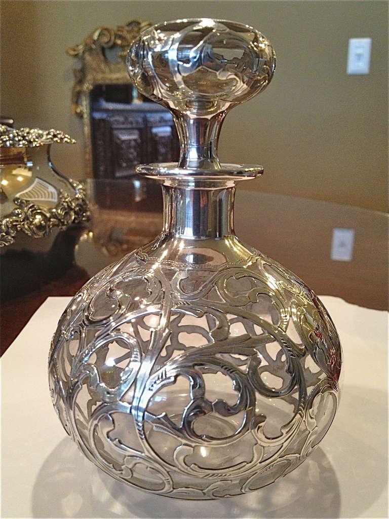 I love this piece because of the beautiful pattern in the silver work as well as the amount of silver involved, the chasing on the finish is wonderful. Love the shape of the stopper, all together a great example of Art Nouveau.