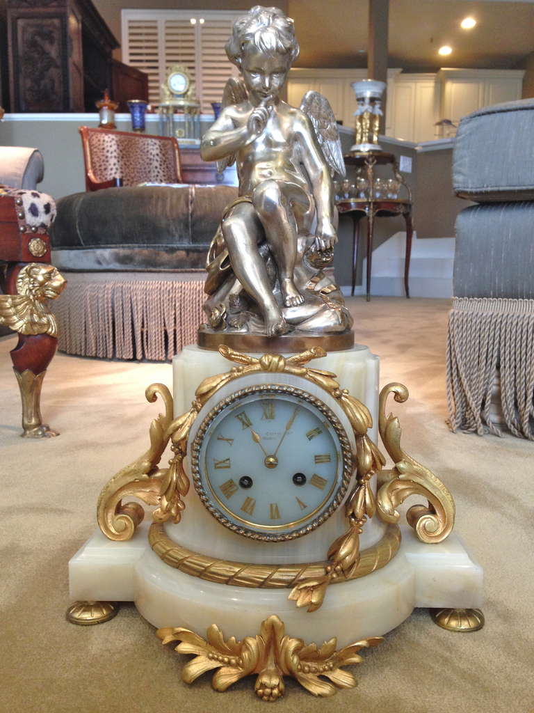 This lovely mantle clock with its duel color finish is unusual, we love the combination of the gold gilt and silver plate over the very finely cast bronzes. The clock maker is taking second billing on this piece, this is common and makes good sense,