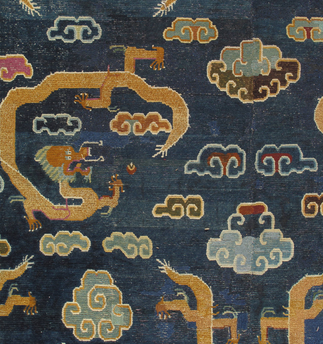 There are very few large, room-sized Tibetan carpets of any real age. This carpet has a four-two-four dragon array on a deep blue field. The dragons appear singly on smaller Tibetan rugs. There are volute edged clouds around and between the dragons