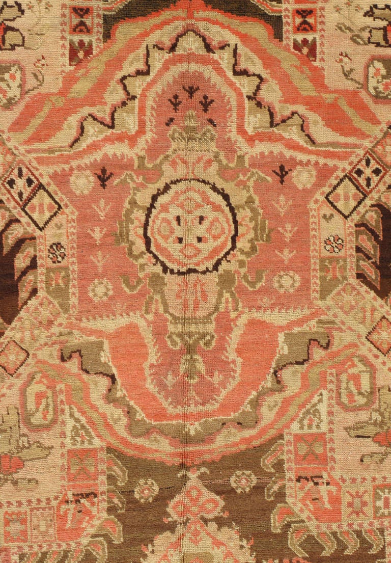 The central panel with a repeating open geometric design with diamond-shaped reserves and oval discs at the corners on a dark brown and beige ground, within foliate scrolled borders with tones of brown, cream apricot and coral.