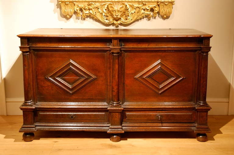 A rare Virginia walnut chest of architectural form, the lifting lid above panels decorated with lozenge moldings, divided by pilasters, below which are two drawers, the whole standing on original bun feet. All the metal work including the locks is