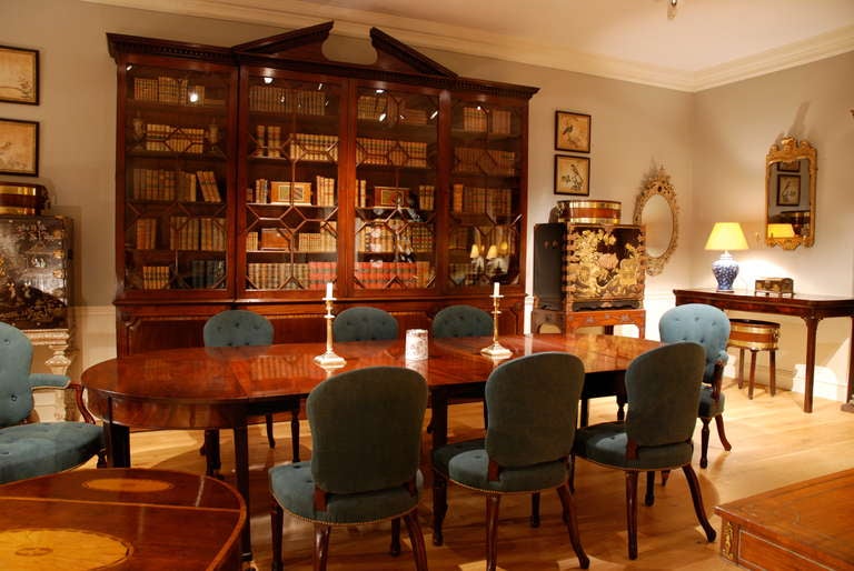 A mahogany breakfront bookcase having a broken arched pediment and dental frieze above four glazed doors, the lower section having crossbanded fielded panels, carved rosettes to the corners, the whole standing on a plinth base. Circa 1760.