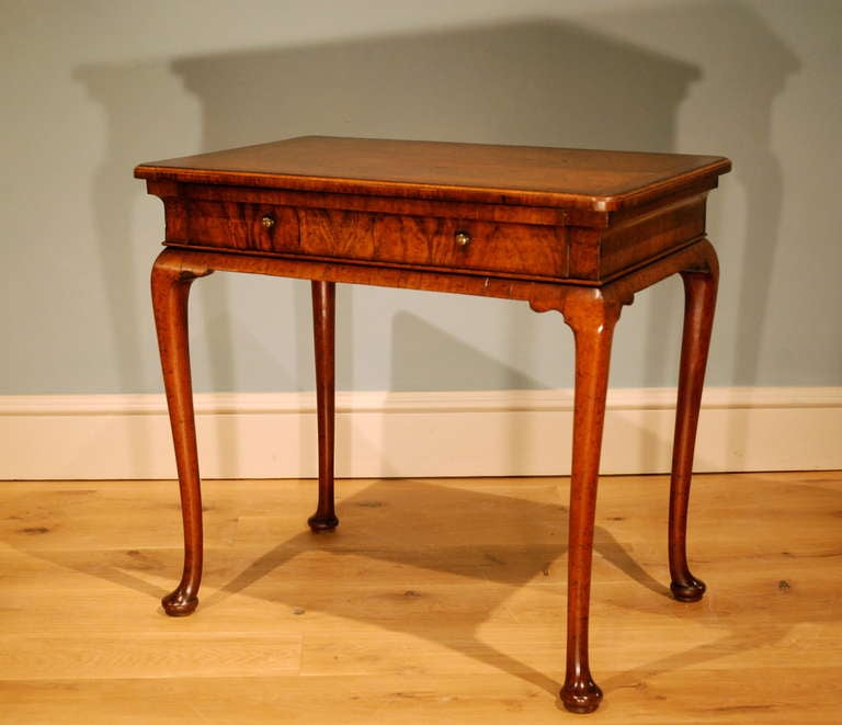 A fine veneered walnut side table, the top cross banded with herringbone and crossbanding, the vertically veneered frieze having an oak lined drawer, a finely moulded skirt leading to well drawn cabriole legs ending in pad feet. Circa 1725.
