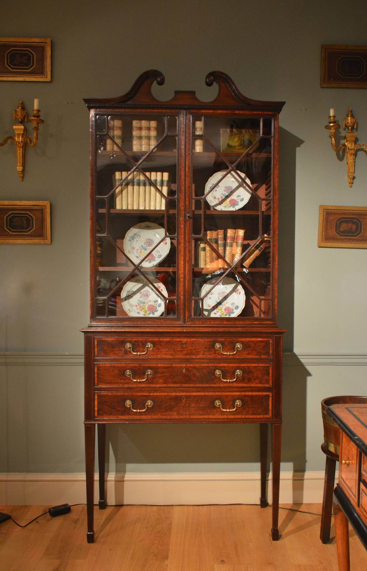 A small mahogany secretaire bookcase of architectural form with fitted writing drawer, the whole crossbanded throughout in tulip wood with stringing, standing on elegantly tapered legs. Circa 1780.