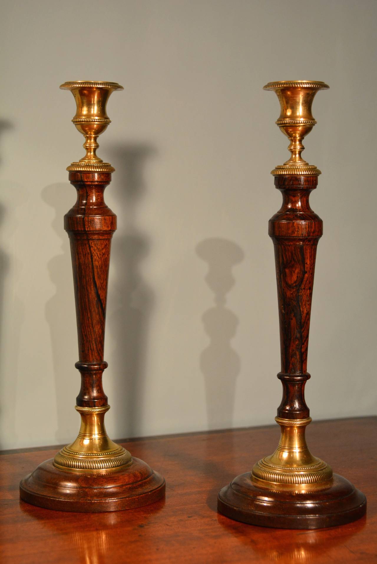 A fine pair of late 18th century candlesticks. The turned mahogany bases having a large milled lacquered brass collar, the turned rosewood stem surmounted by a turned milled lacquered brass sconce. These candle sticks have excellent colour and