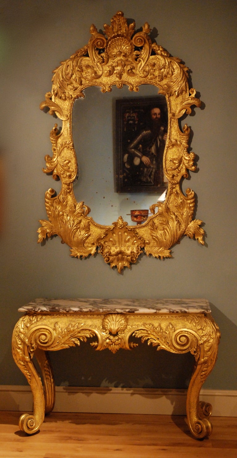 A carved gilt wood mirror the shaped plate surrounded by a strongly carved frame variously decorated with scrolling acanthus and motifs alluding to water. Circa 1735.
44