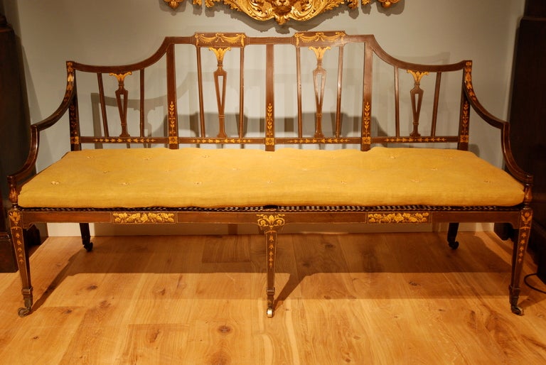A painted settee with neoclassical gilt decoration, the caned seat with a mustard colored tufted squab cushion,
circa 1790.