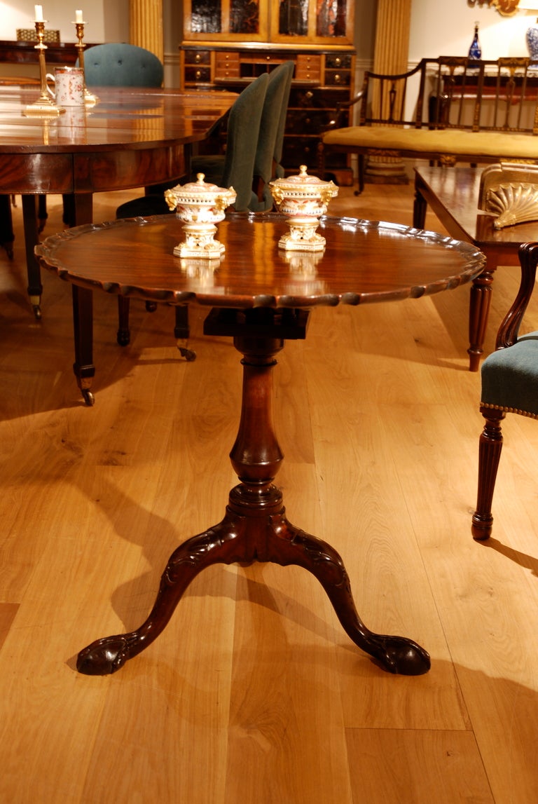 A mahogany piecrust tripod table with birdcage support standing on a vase shaped stem, the legs carved with shells to the knees and confidently spreading claw and ball feet.
Circa 1760.