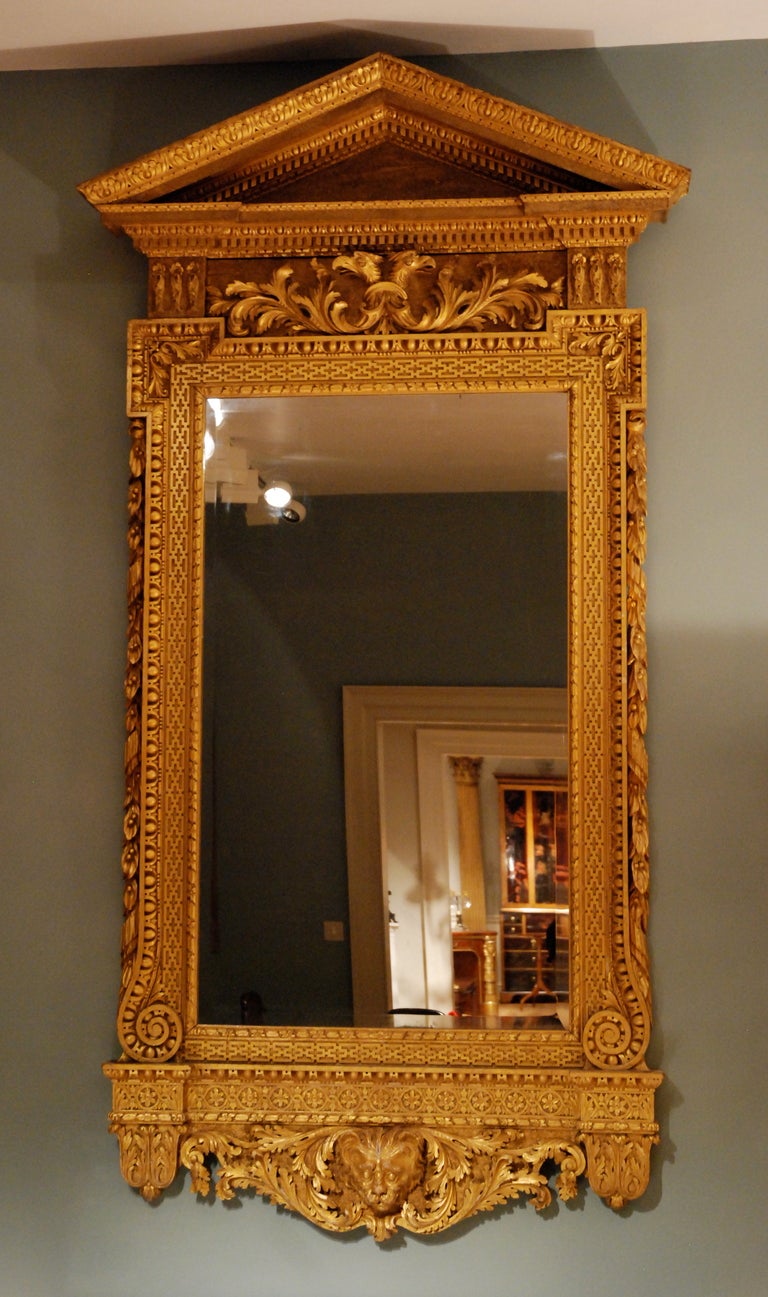 A large fine carved giltwood architectural mirror in the Kentian manner, having an arched pediment the frame adorned with various classical motifs the base centred by a carved lions mask,
circa 1730.