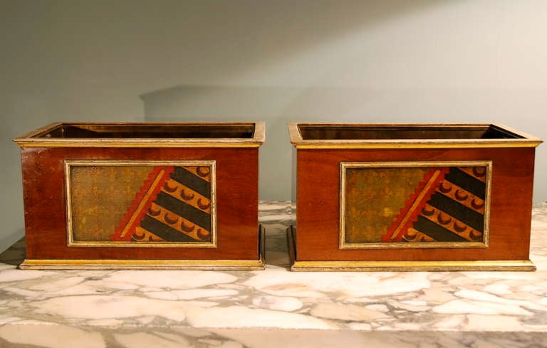 A pair of rectangular mahogany jardinieres with gilt mouldings having faux armorial panels to the front face. With brass liners. Circa 1820.