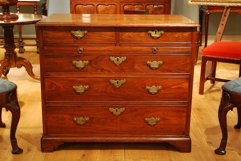 A George II chest of drawers, the moulded top above two short drawers below which is a full length slide with three long drawers below, the whole standing on bracket feet with re-entrant corners. The top, slide and drawers of solid Huanghuali. The