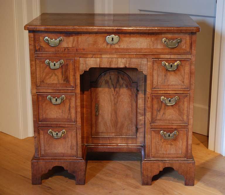 An early 18th Century veneered walnut kneehole desk/ dressing table, the quarter veneered top having herringbone inlay and crossbanding, with one long frieze drawer below, below which is a secret drawer below which, is the kneehole which contains an