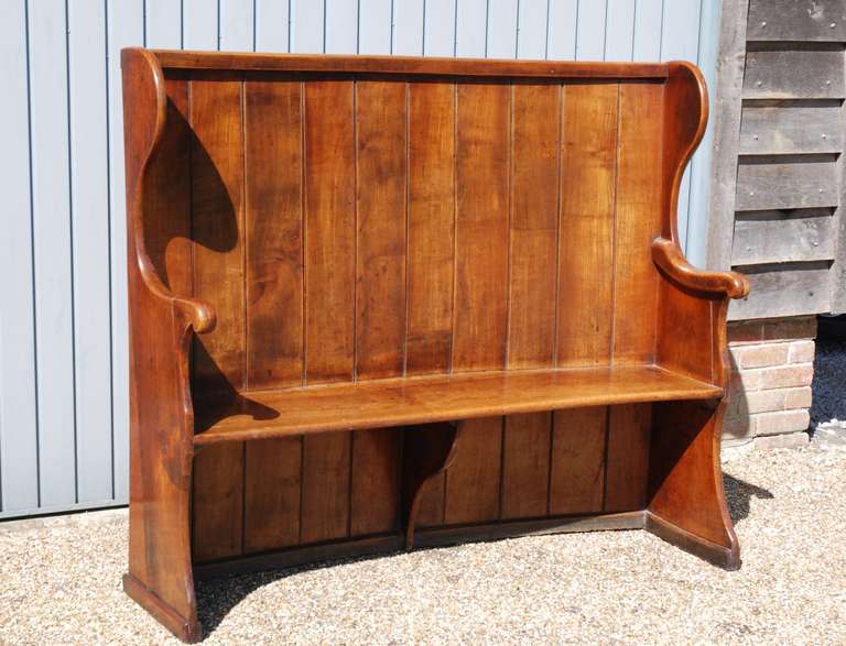 A late 18th century fruitwood settle of curved form having superb colour and patination.