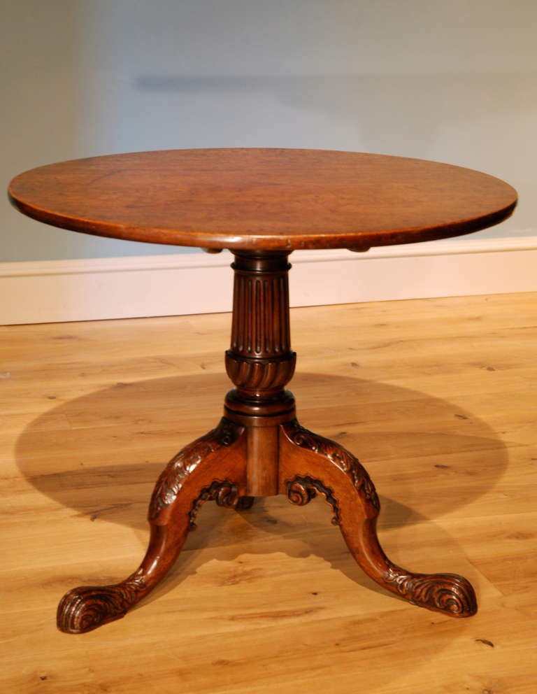 A circular mahogany tripod table standing on a fluted and riven column supported by outscrolling legs carved with acanthus decoration. English Circa 1750.