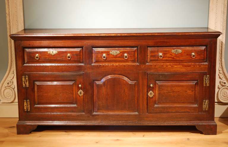 A good George II patinated pine dresser, having three drawers below which are two cupboard doors with a central fixed panel. The whole standing on bracket feet. Unlike many pine dressers, this dresser has never been painted, and is of very good