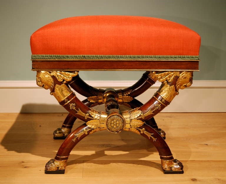 A very fine late 18th Century French mahogany X frame stool in the Empire style having finely carved gilt enrichments with high quality ormolu mounts. Circa 1800.