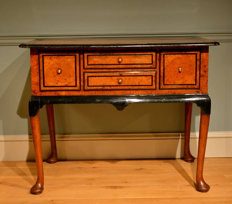 A mid-18th Century Anglo-Dutch four drawer side table, top front and sides veneered in golden burr amboyna banded and with mouldings of ebonized beech standing on turned beech legs terminating in strong pad feet. Circa 1740.