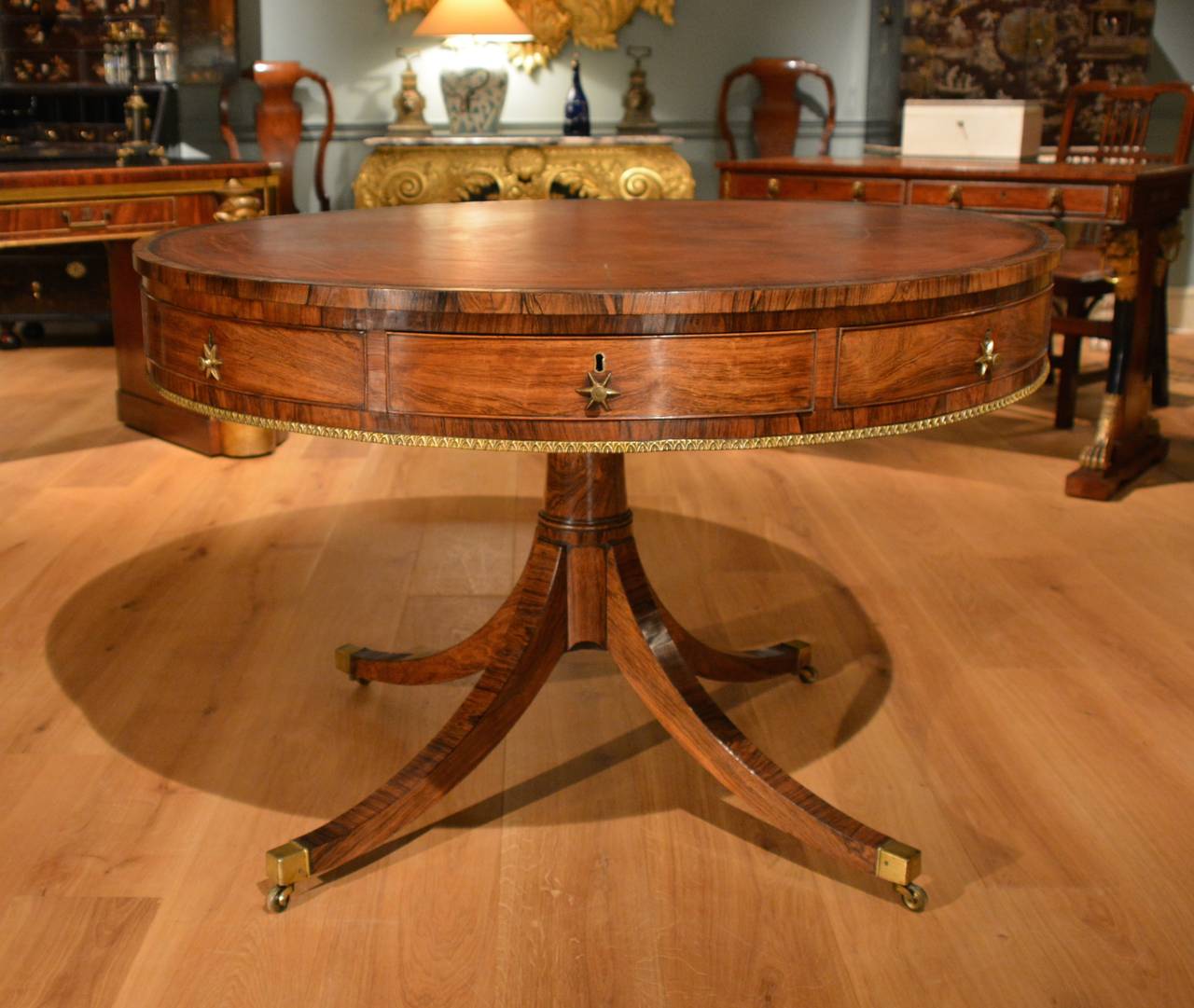 A fine George III drum or library table, the circular revolving top crossbanded and leather lined with four real and four dummy drawers to the frieze all retaining their original handles, below which is a lacquered brass lotus leaf banding, the