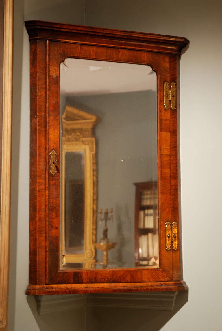 A corner cupboard veneered in finely figured walnut with it's original mirrored door.
Circa 1725.