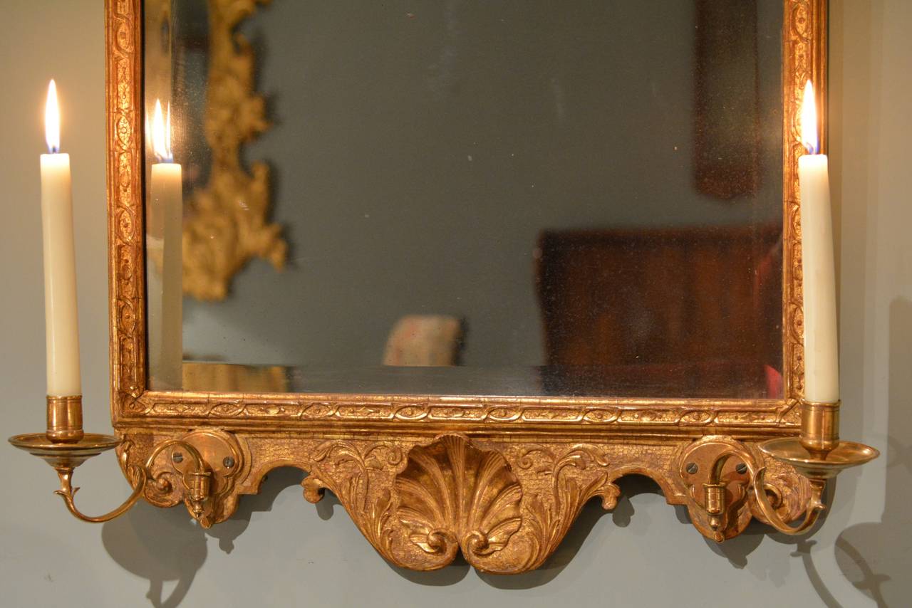 A finely carved gilt gesso mirror having candle arms to the base, circa 1720.