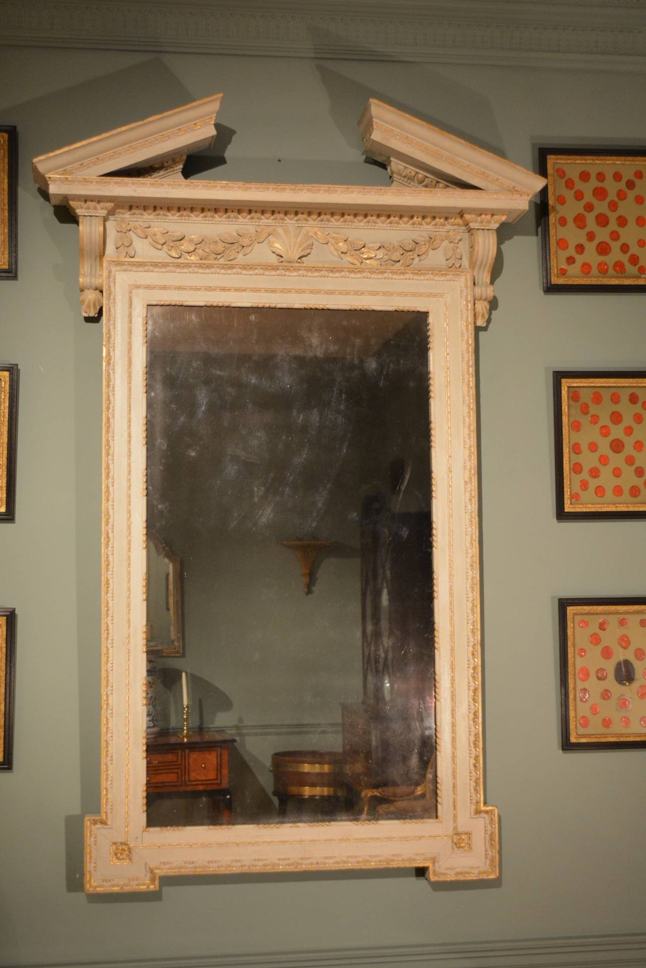 A large architectural 'Kentian' mirror, the broken pediment above a frieze of shell and swags, the whole frame retaining its original painted finish and gilt enrichments and also retaining its original mirror plate.

English, circa 1740.