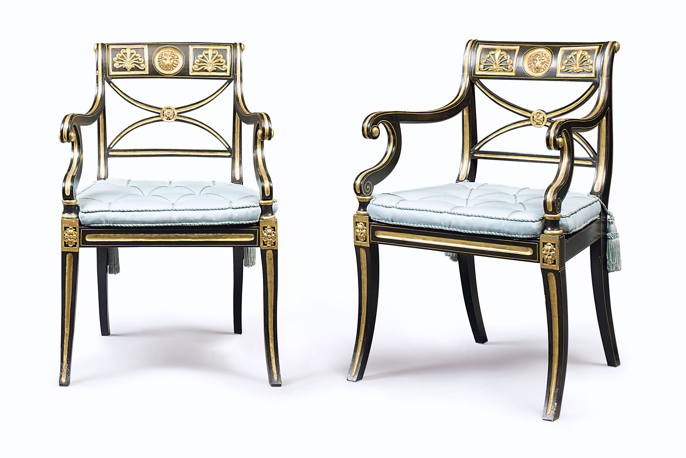 A pair of Regency ebonised and parcel-gilt open arm chairs