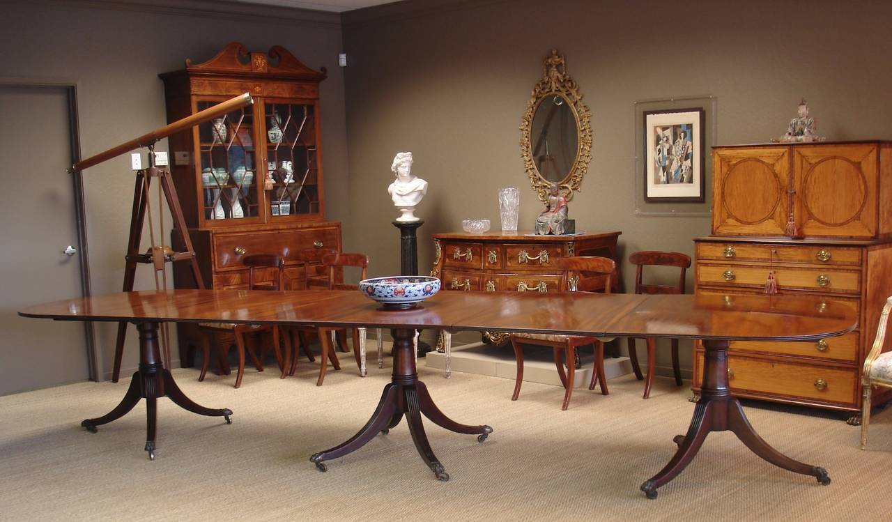 Late George III mahogany triple pedestal dining table of large size. The well-figured top is accented with ebony stringing, with two additional ebony strung leaves, all supported by 'gun barrel' column supports, terminating in reeded splay legs,