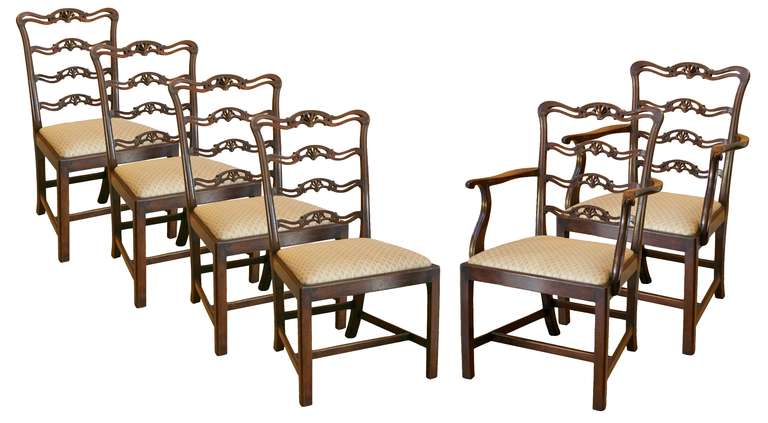 A set of six late George III/ Regency style mahogany ladder back dining chairs. The shaped top rail enclosing pierced horizontal splats with carved anthemion detail. The drop in seats on square section legs united by H-stretcher. The set consists of